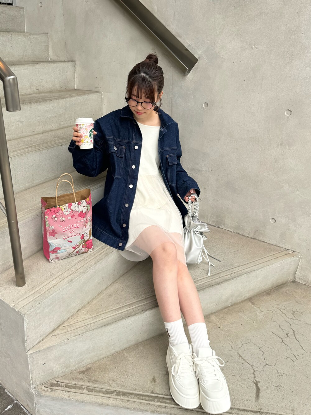 ブルー系のデニムジャケット、ホワイト系のトップス、ホワイト系のスニーカーを着用したレディースの冬コーディネートの5枚目の写真