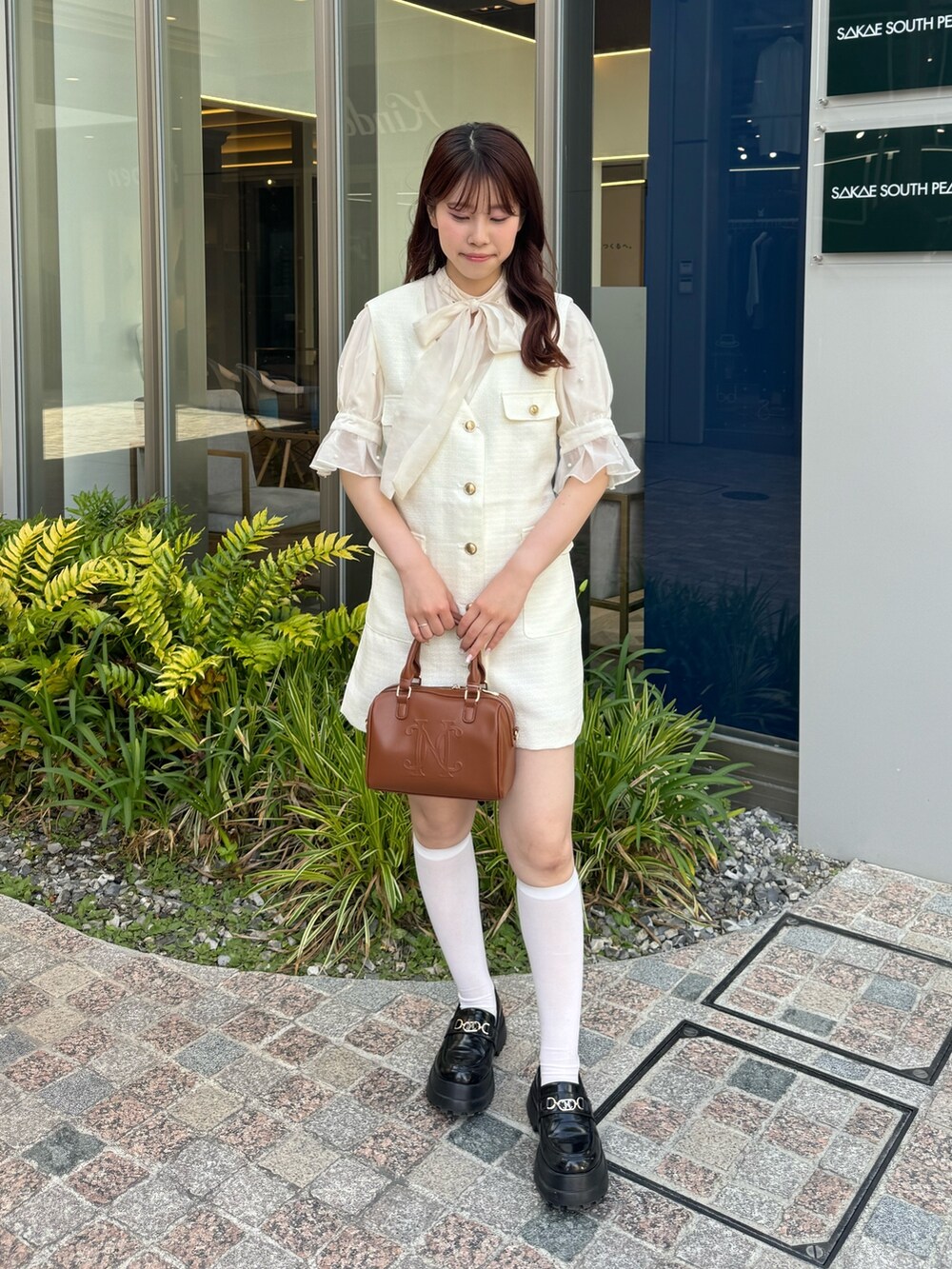 ホワイト系のシャツ/ブラウス、ホワイト系のベスト、ブラウン系のボストンバッグを着用したレディースの夏コーディネートの2枚目の写真