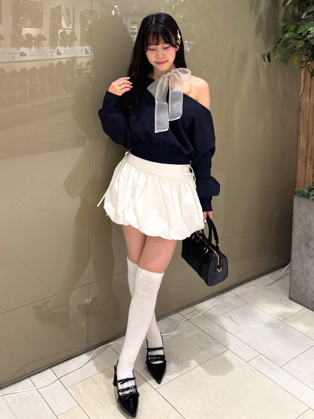 ブルー系のTシャツ/カットソー、ホワイト系のスカート、ブラック系のボストンバッグを着用したレディースの冬コーディネートの4枚目の写真