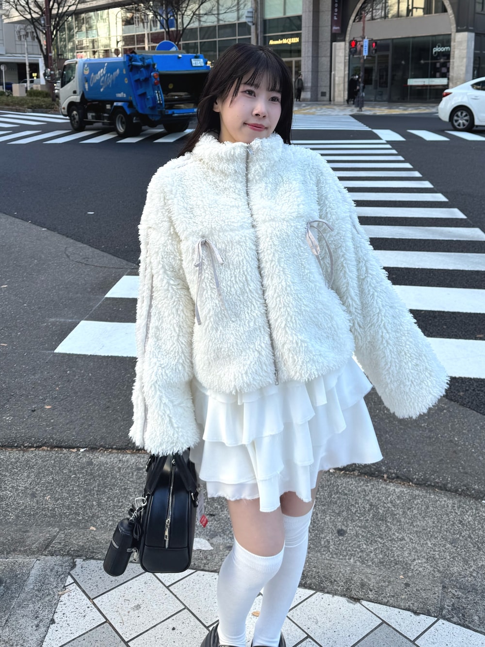 ホワイト系のブルゾン、ホワイト系のスカート、ブラック系のハンドバッグを着用したレディースの冬コーディネートの5枚目の写真