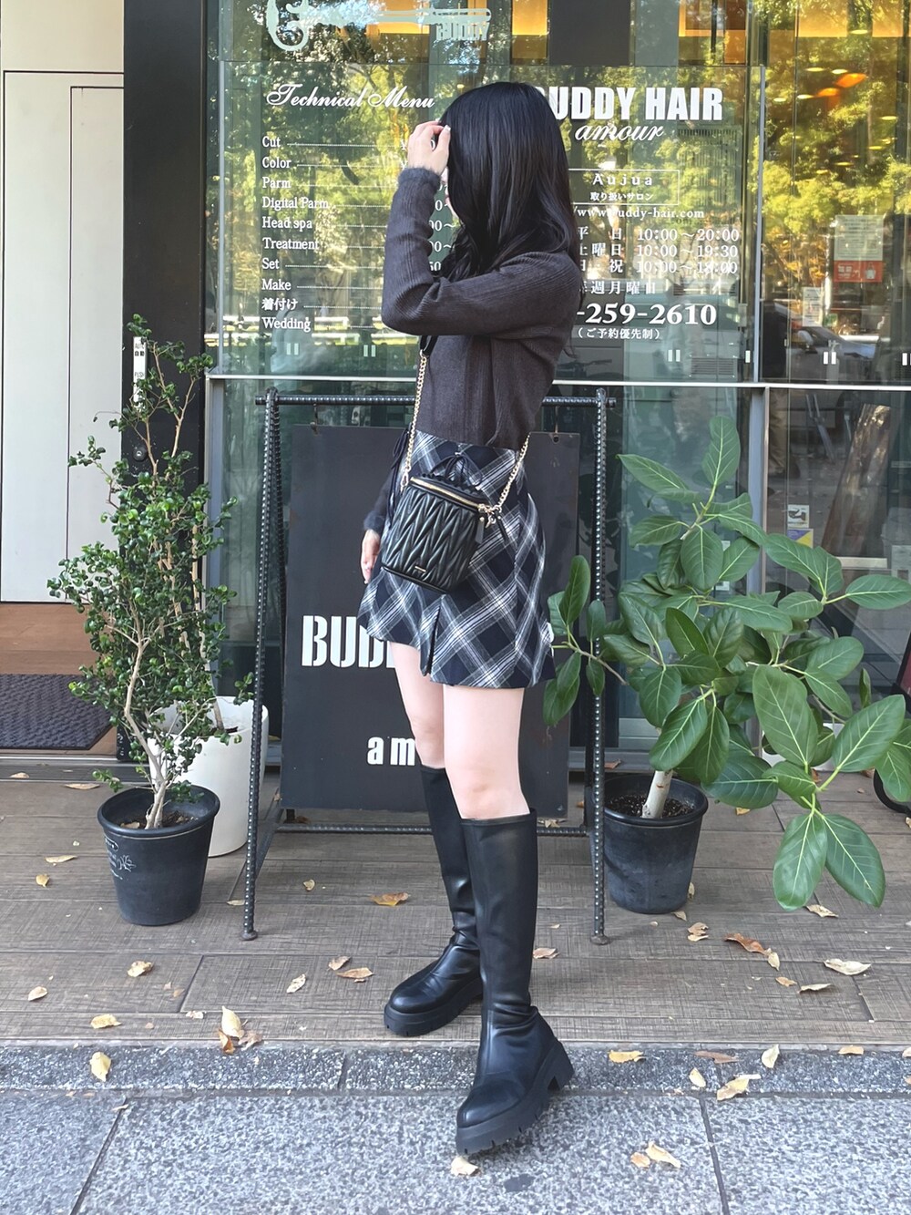グレー系のニット/セーター、ブルー系のスカート、ブラック系のショルダーバッグを着用したレディースの秋コーディネートの2枚目の写真