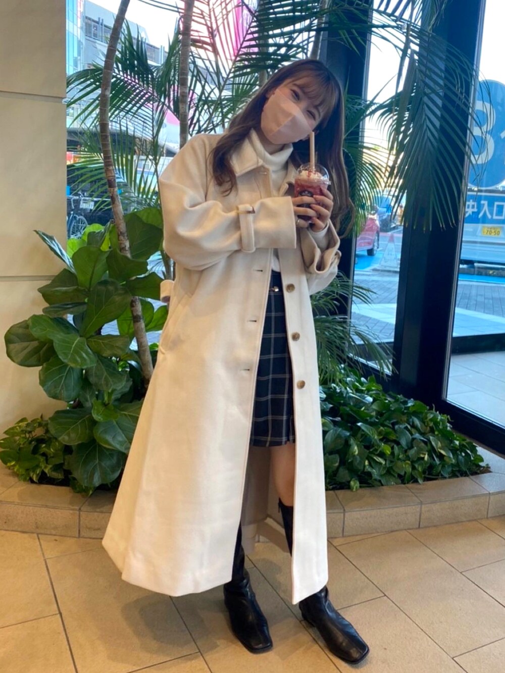 ホワイト系のステンカラーコートを着用したレディースの秋コーディネートの2枚目の写真