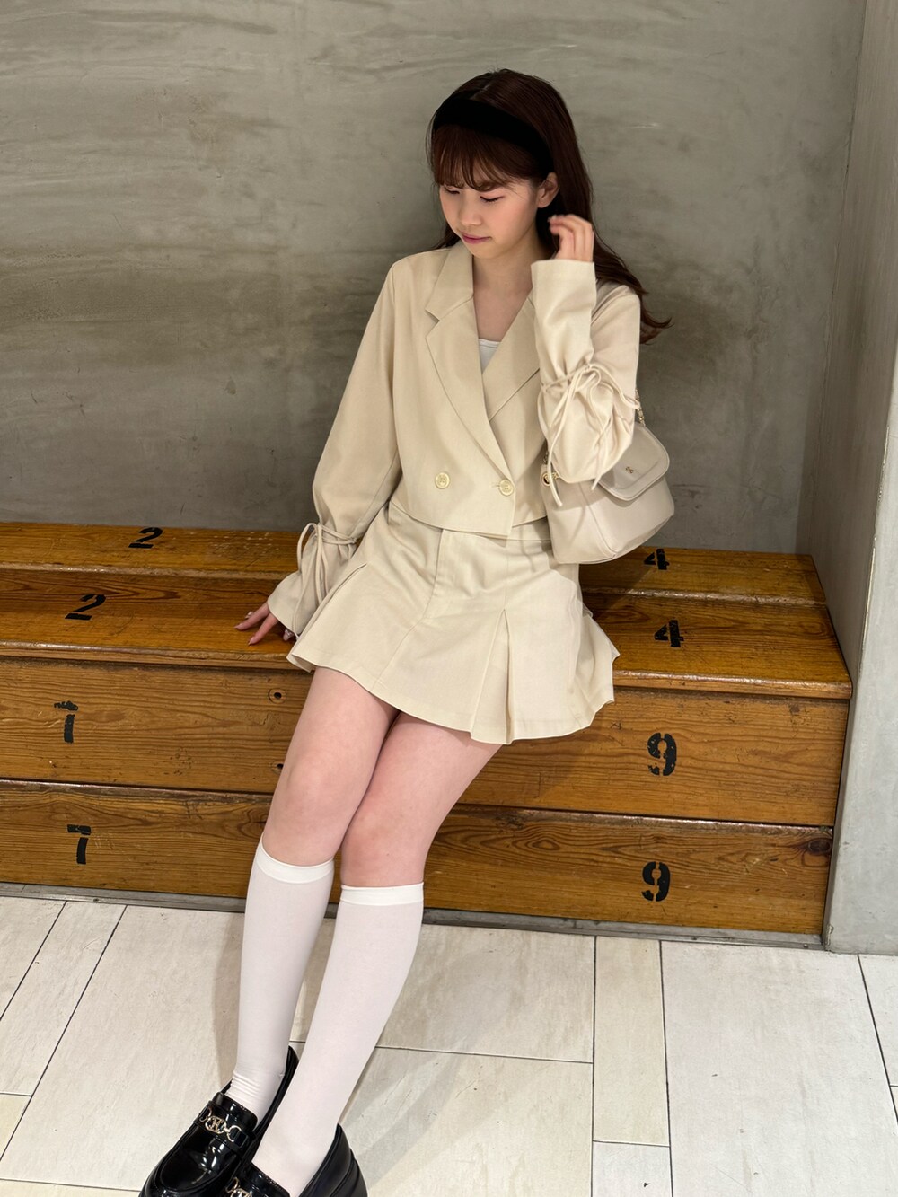 ホワイト系のテーラードジャケット、ホワイト系のスカート、ベージュ系のショルダーバッグを着用したレディースの春コーディネートの4枚目の写真