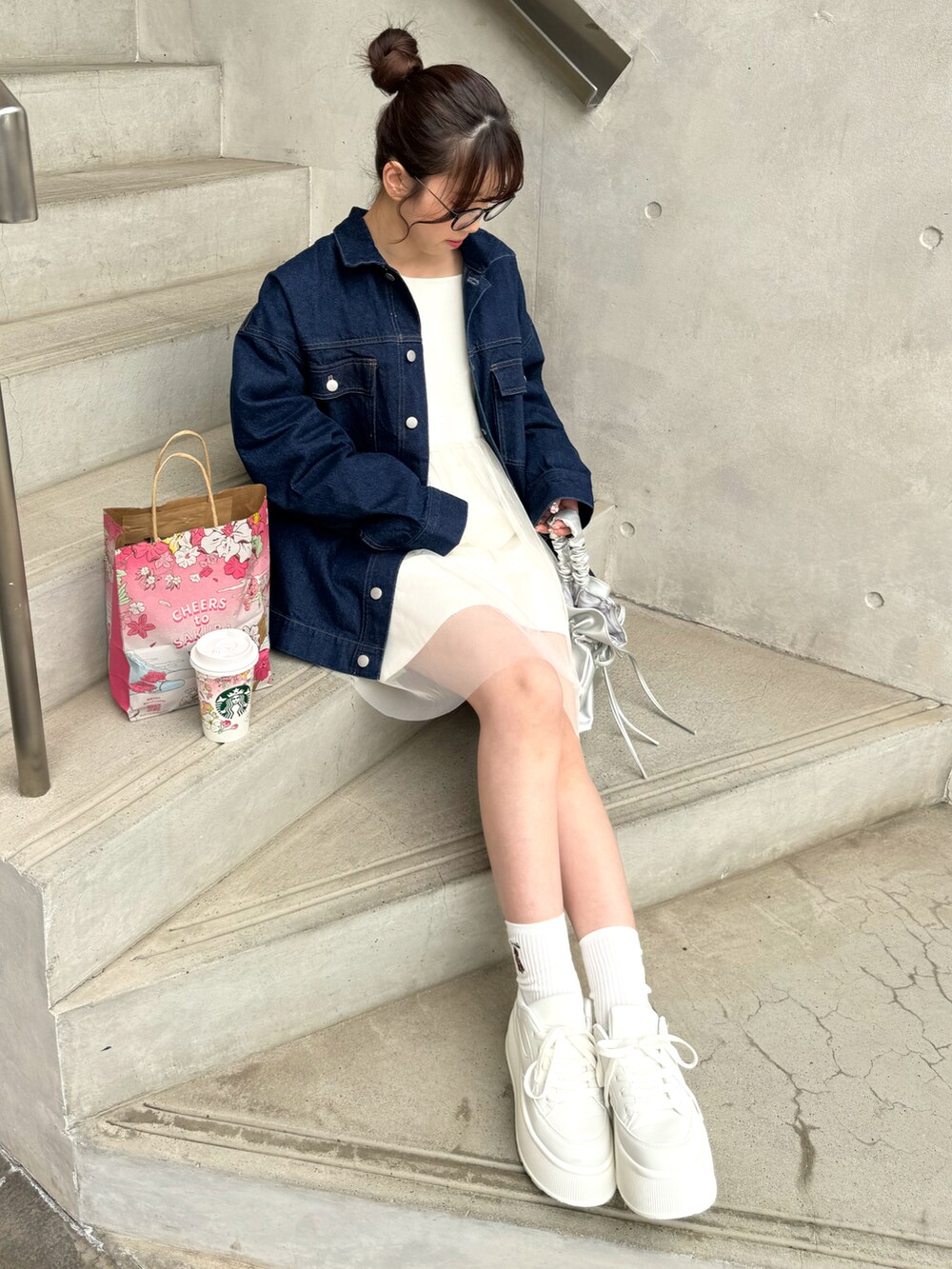 ブルー系のデニムジャケット、ホワイト系のトップス、ホワイト系のスニーカーを着用したレディースの冬コーディネートの2枚目の写真