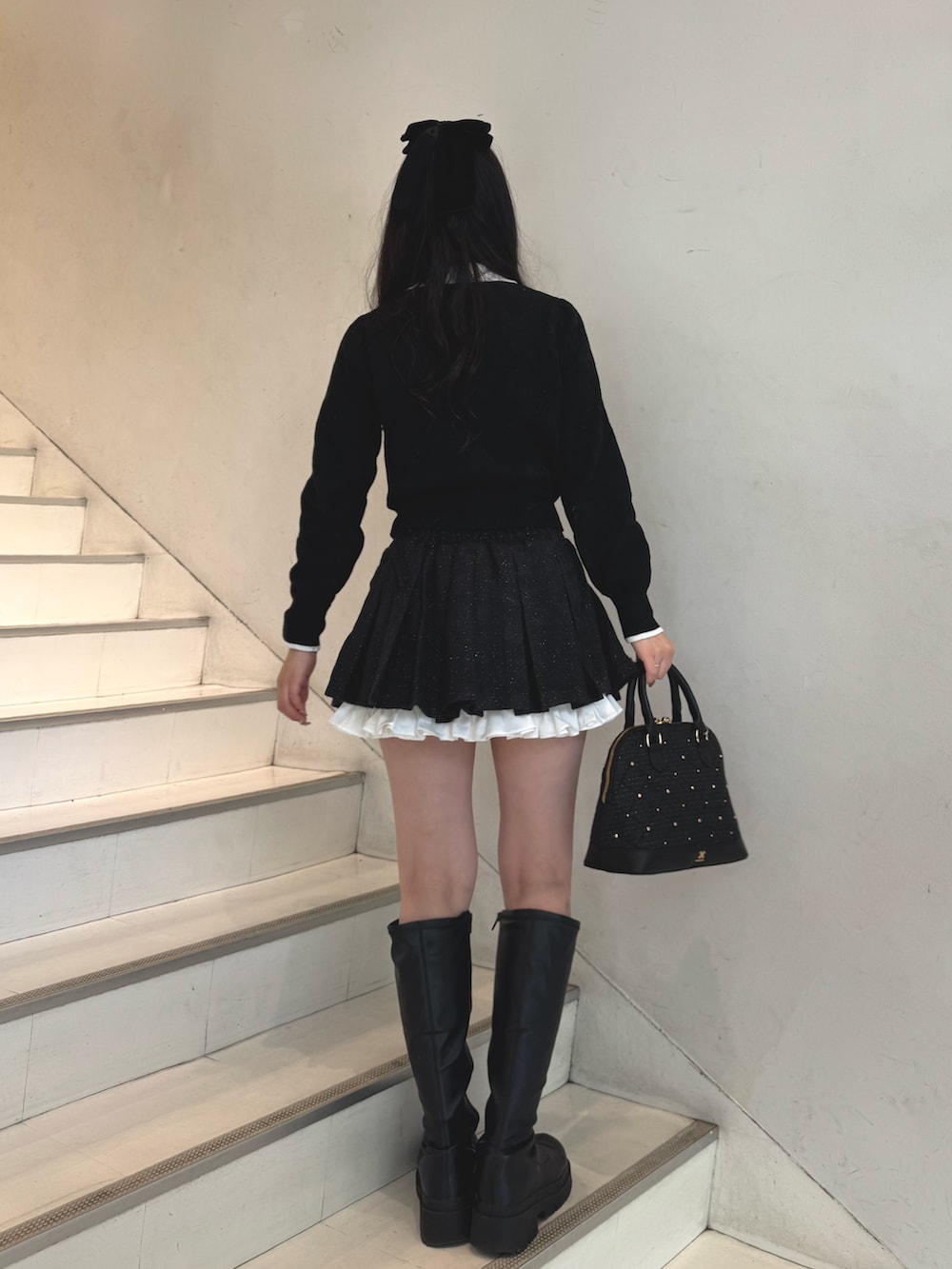 ブラック系のニット/セーター、ブラック系のスカート、ブラック系のハンドバッグを着用したレディースの冬コーディネートの5枚目の写真