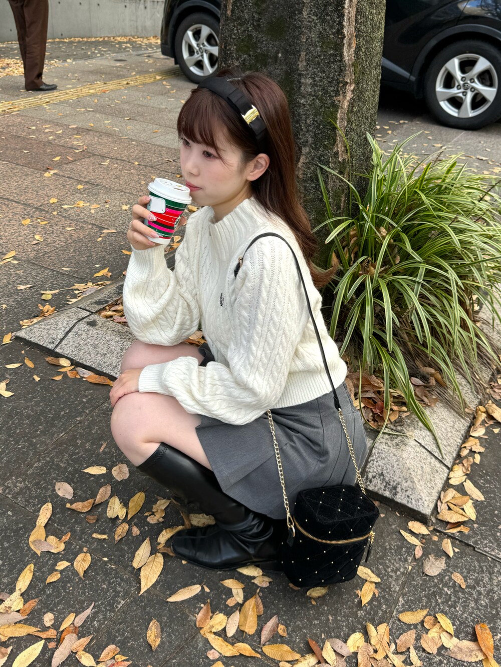 ホワイト系のニット/セーター、グレー系のスカート、ブラック系のショルダーバッグを着用したレディースの冬コーディネートの5枚目の写真