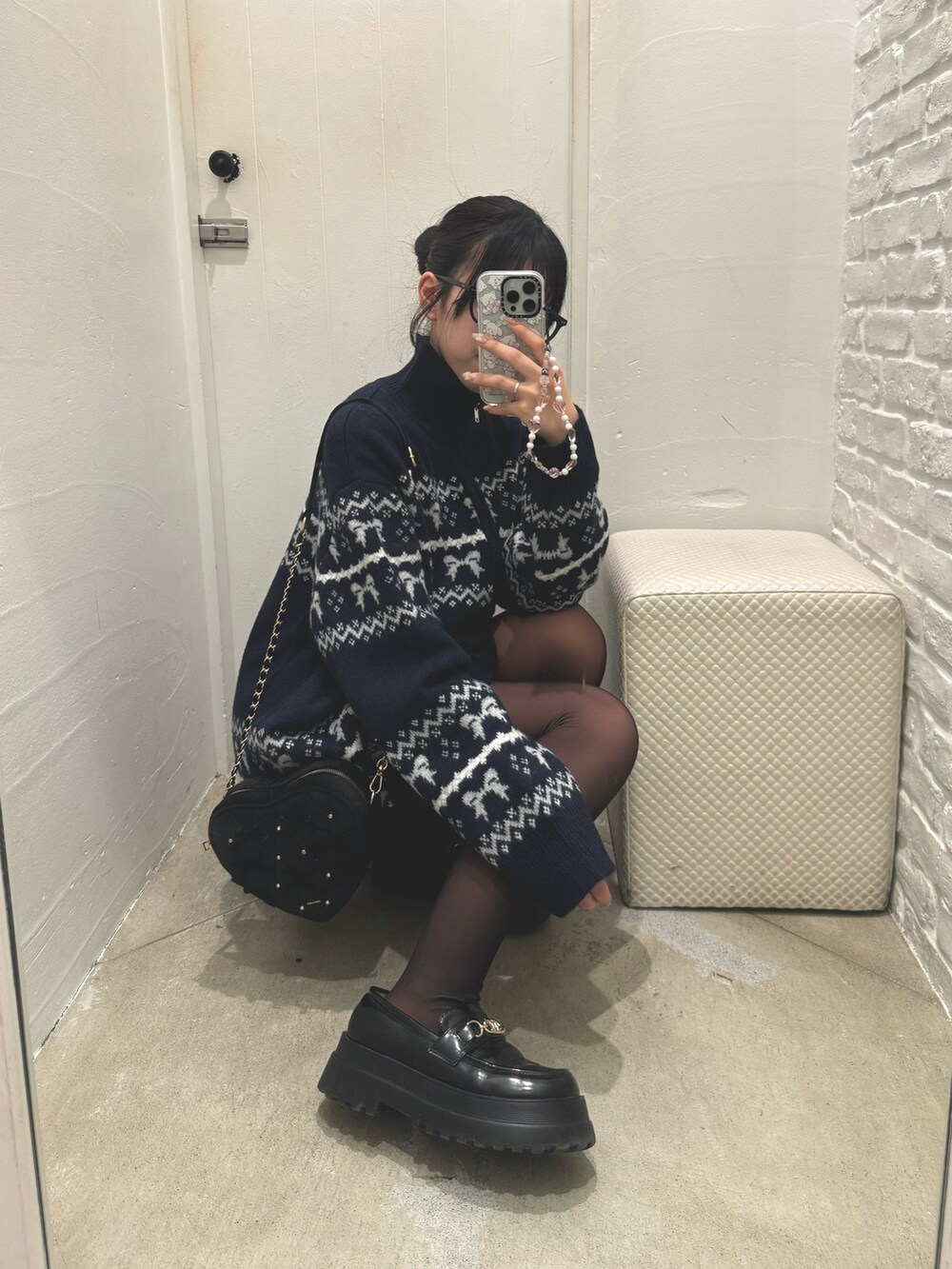 ブルー系のチュニック、ブラック系のショルダーバッグを着用したレディースの冬コーディネートの2枚目の写真