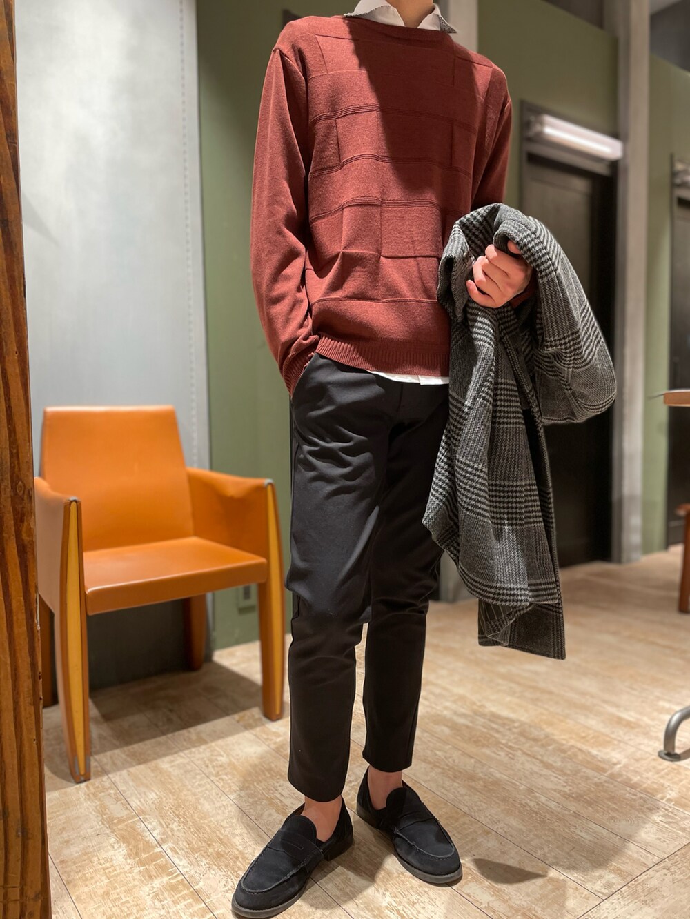 グレー系のチェスターコート、レッド系のニット/セーター、ホワイト系のシャツ/ブラウスを着用したメンズの冬コーディネートの2枚目の写真