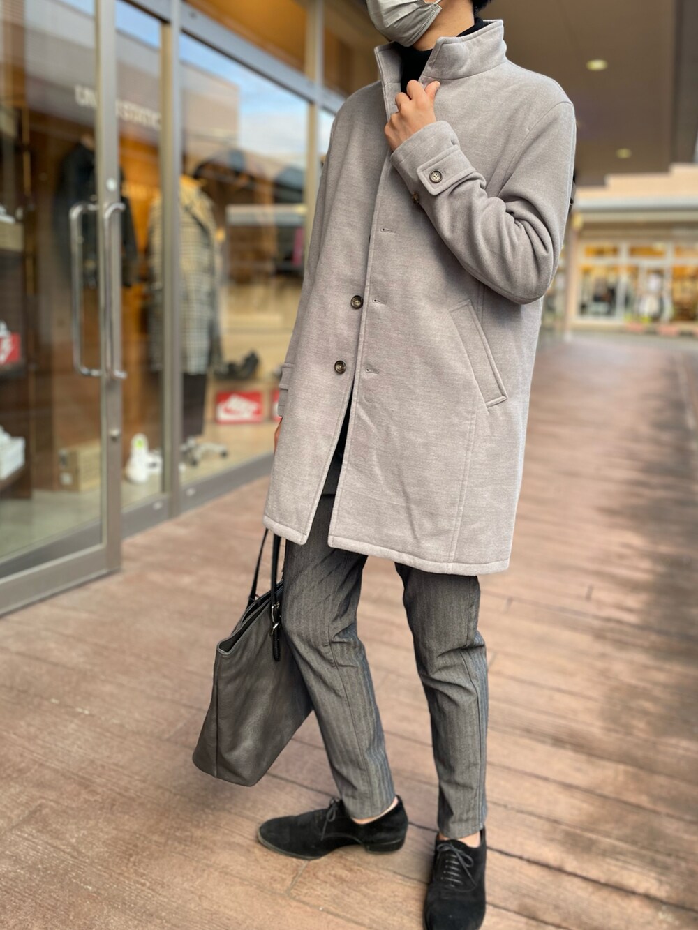 グレー系のチェスターコート、ブラック系のニット/セーター、グレー系のスラックスを着用したメンズの冬コーディネートの2枚目の写真