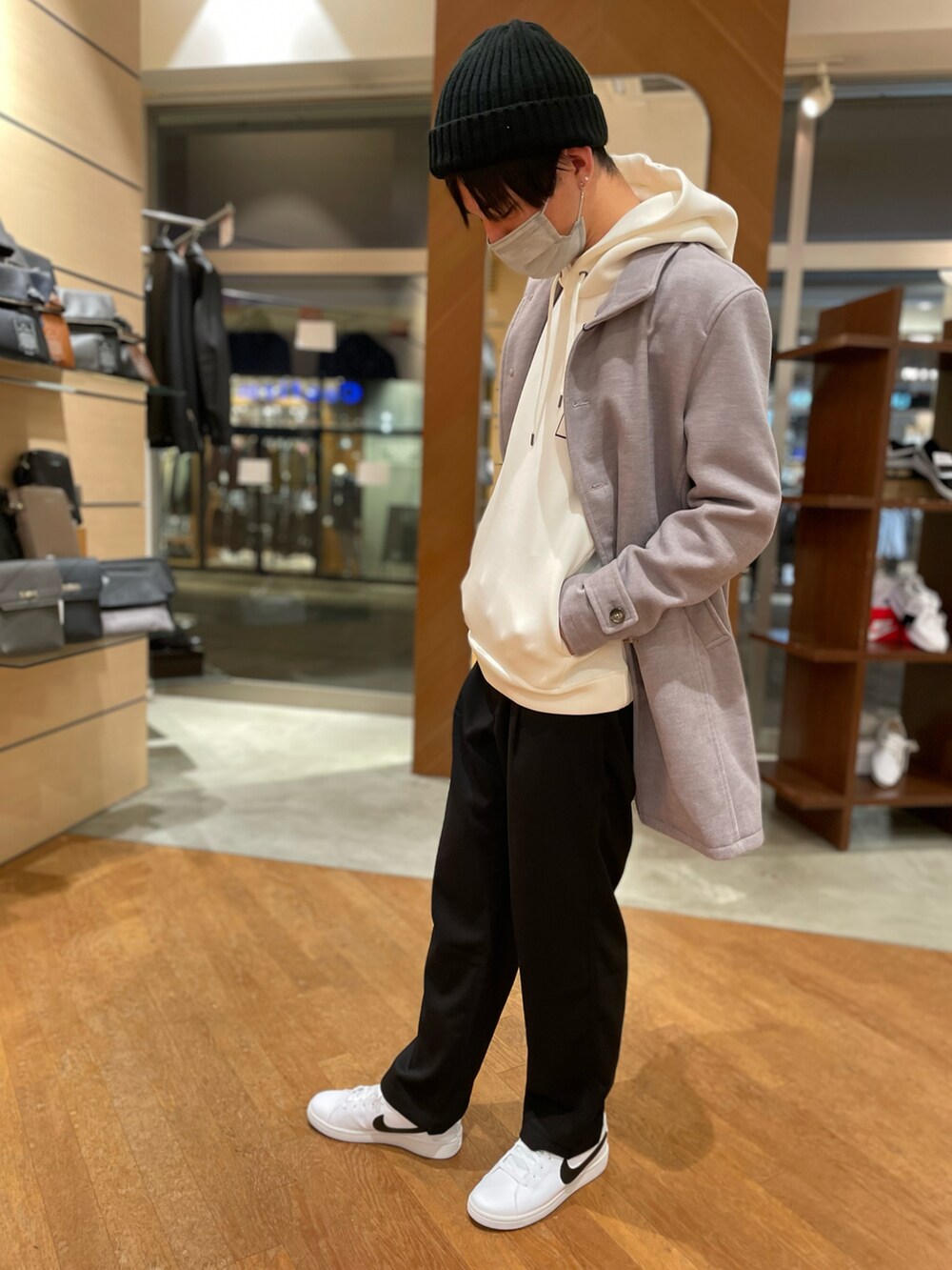 グレー系のチェスターコート、ホワイト系のパーカー、ブラック系のスラックスを着用したメンズの冬コーディネートの2枚目の写真