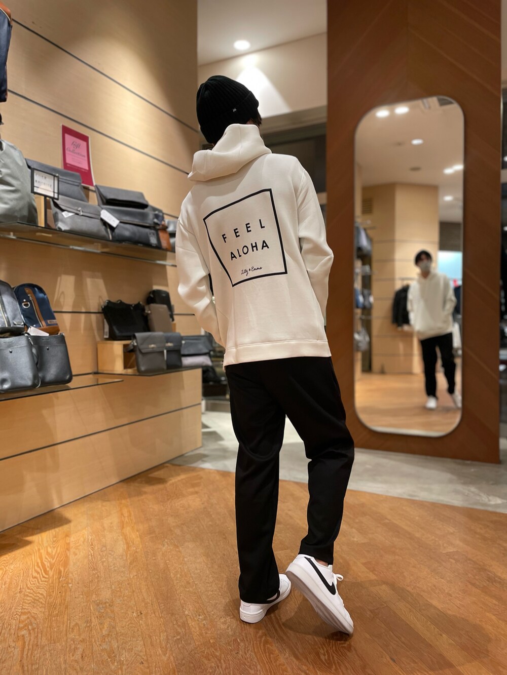 グレー系のチェスターコート、ホワイト系のパーカー、ブラック系のスラックスを着用したメンズの冬コーディネートの3枚目の写真