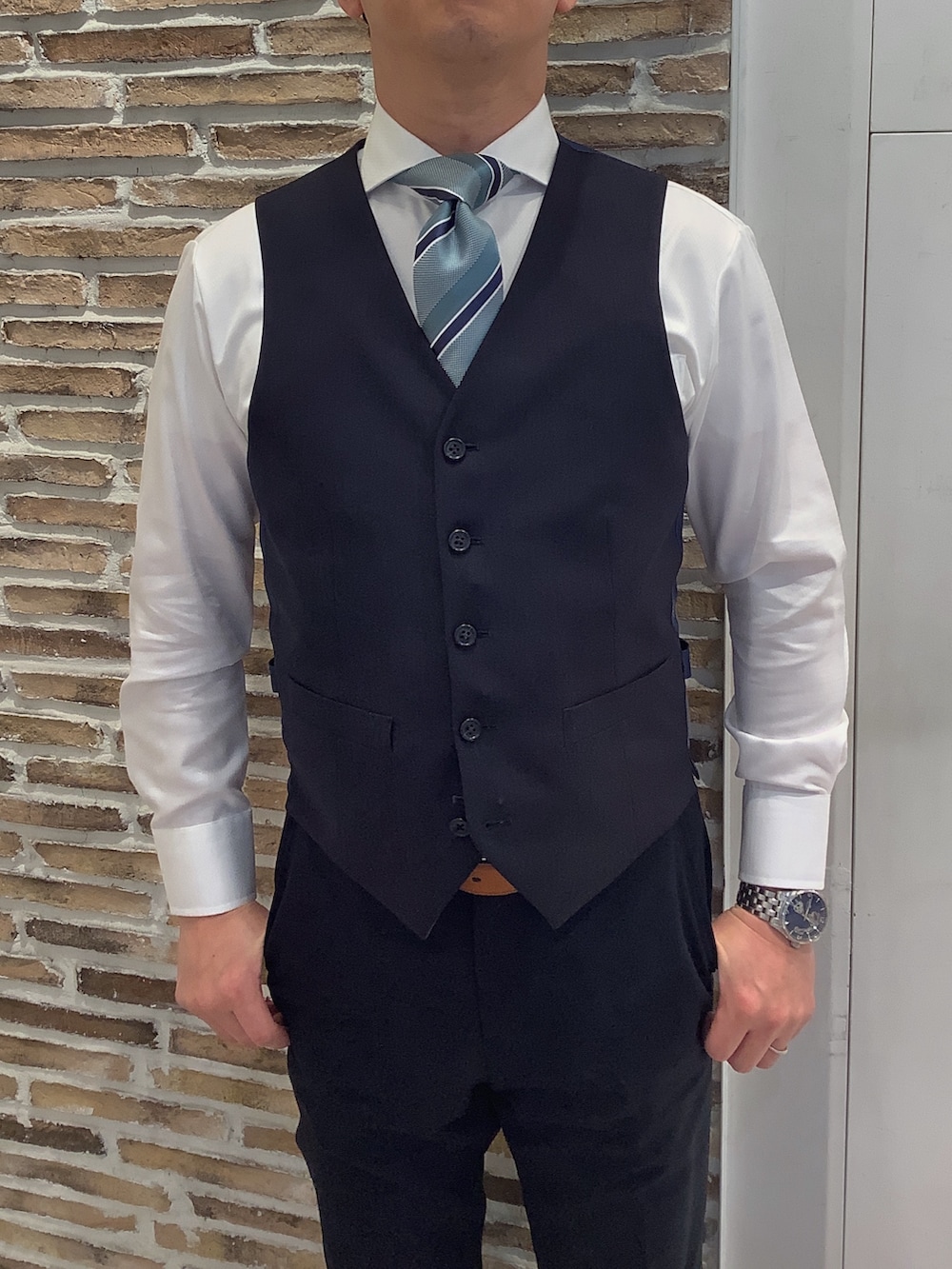 ホワイト系のビジネスシャツ、グリーン系のネクタイを着用したメンズの冬コーディネートの2枚目の写真