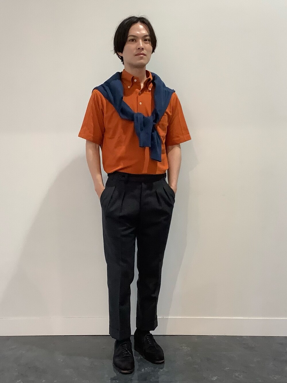 オレンジ系のポロシャツ、ブルー系のカーディガン/ボレロを着用したメンズの夏コーディネートの2枚目の写真