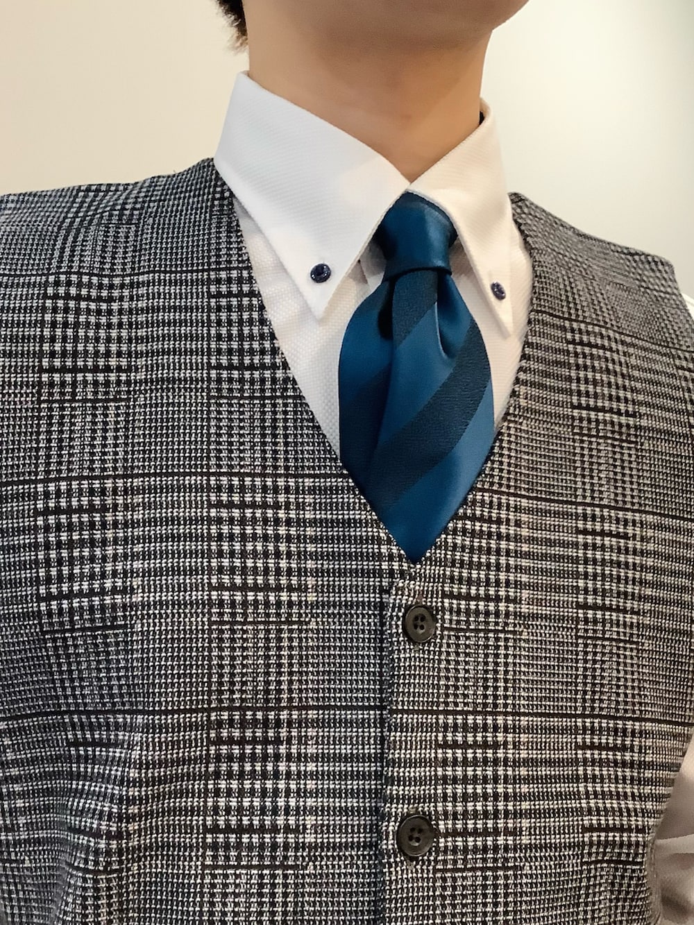 ホワイト系のビジネスシャツ、ブルー系のネクタイ、ブラウン系のベストを着用したメンズの冬コーディネートの3枚目の写真