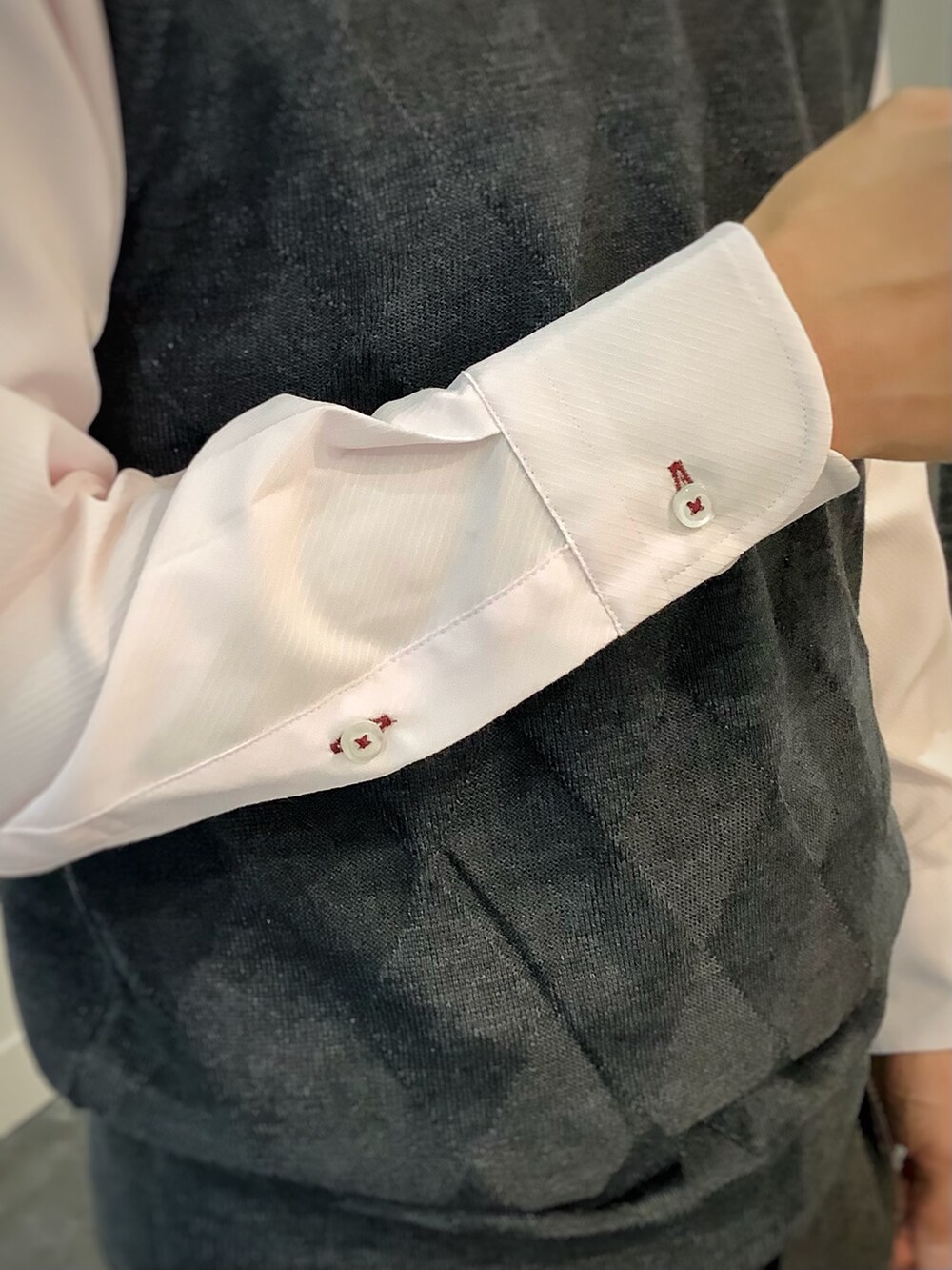 グレー系のベスト、ピンク系のビジネスシャツ、グレー系のビジネスバッグを着用したメンズの秋コーディネートの5枚目の写真