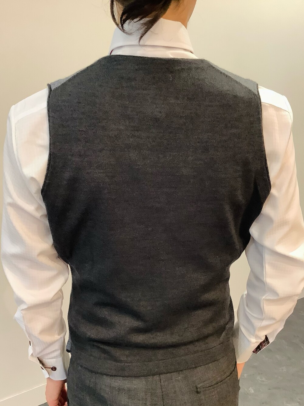 グレー系のベスト、ホワイト系のビジネスシャツ、レッド系のネクタイを着用したメンズの秋コーディネートの3枚目の写真