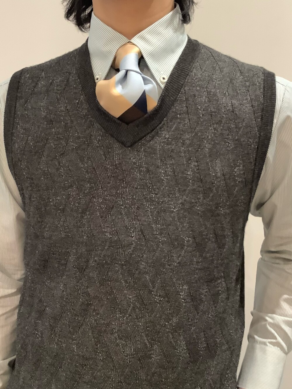 グレー系のベスト、グリーン系のビジネスシャツ、イエロー系のネクタイを着用したメンズの冬コーディネートの2枚目の写真