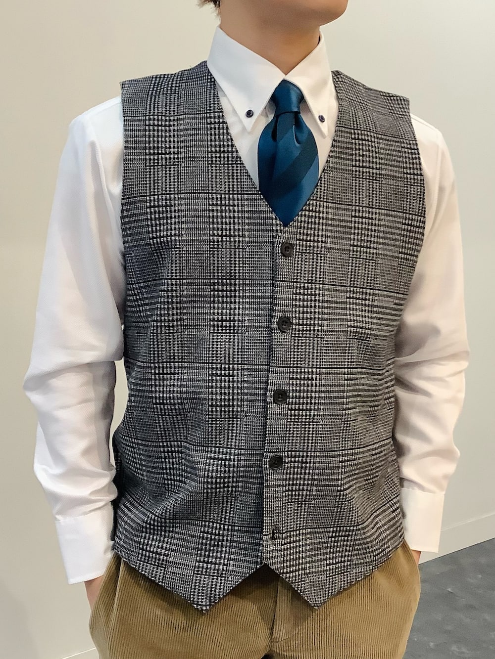 ホワイト系のビジネスシャツ、ブルー系のネクタイ、ブラウン系のベストを着用したメンズの冬コーディネートの2枚目の写真