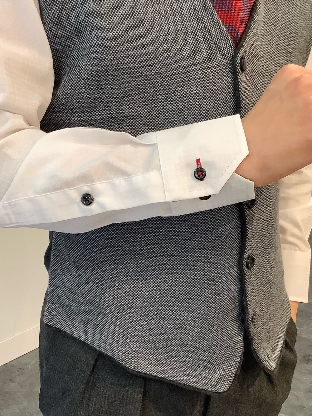 グレー系のベスト、ホワイト系のビジネスシャツ、レッド系のネクタイを着用したメンズの秋コーディネートの5枚目の写真