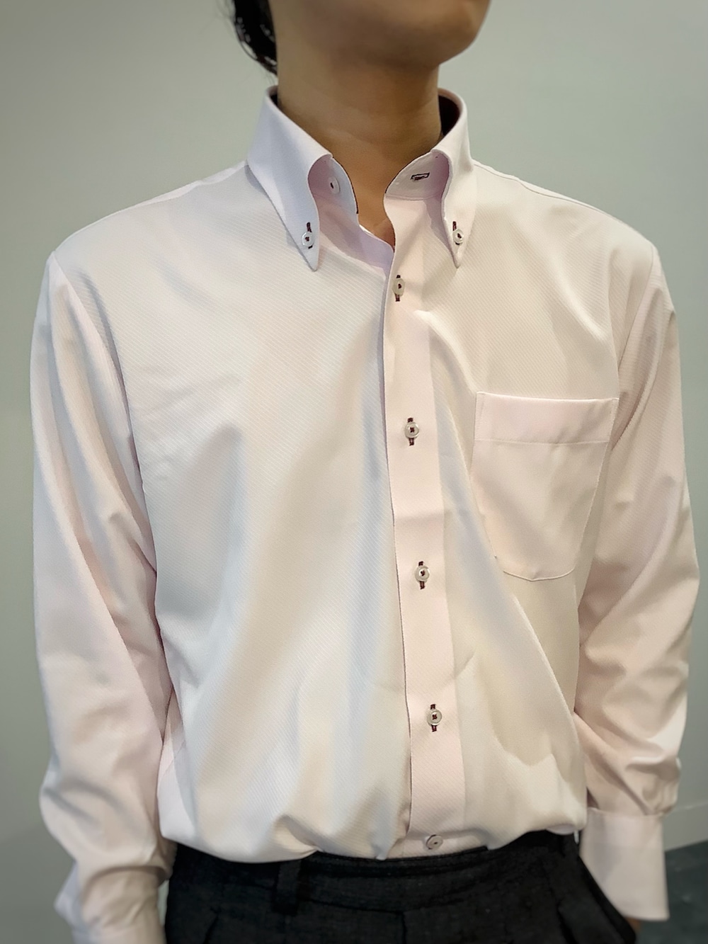 グレー系のベスト、ピンク系のビジネスシャツ、グレー系のビジネスバッグを着用したメンズの秋コーディネートの3枚目の写真