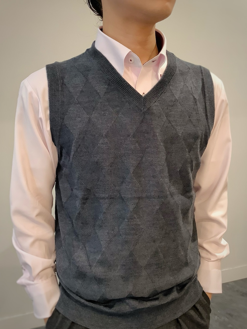 グレー系のベスト、ピンク系のビジネスシャツ、グレー系のビジネスバッグを着用したメンズの秋コーディネートの2枚目の写真