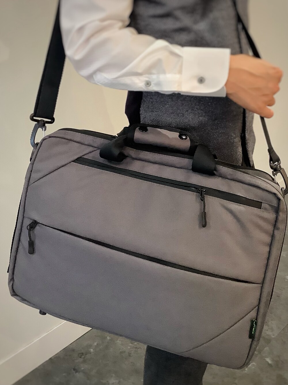 グレー系のベスト、ホワイト系のビジネスシャツ、グレー系のビジネスバッグを着用したメンズの秋コーディネートの7枚目の写真