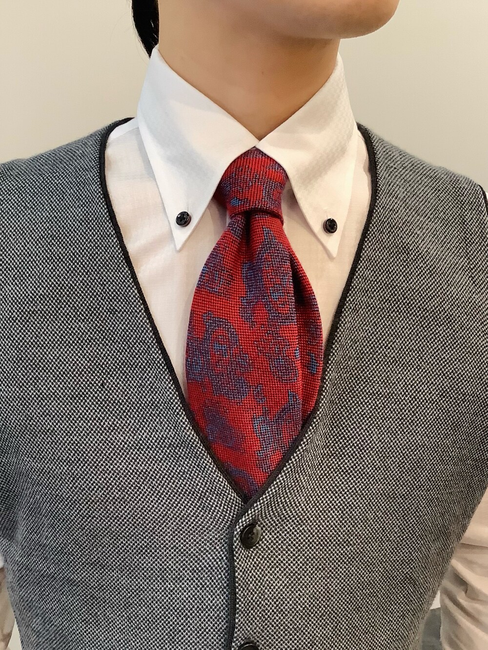 グレー系のベスト、ホワイト系のビジネスシャツ、レッド系のネクタイを着用したメンズの秋コーディネートの4枚目の写真