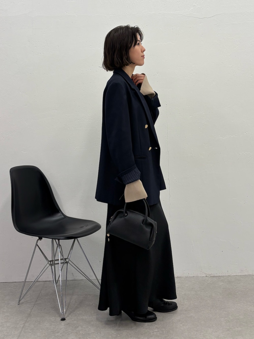 ブラック系のスカート、ブルー系のテーラードジャケット、ブラック系のボストンバッグを着用したレディースの冬コーディネートの4枚目の写真