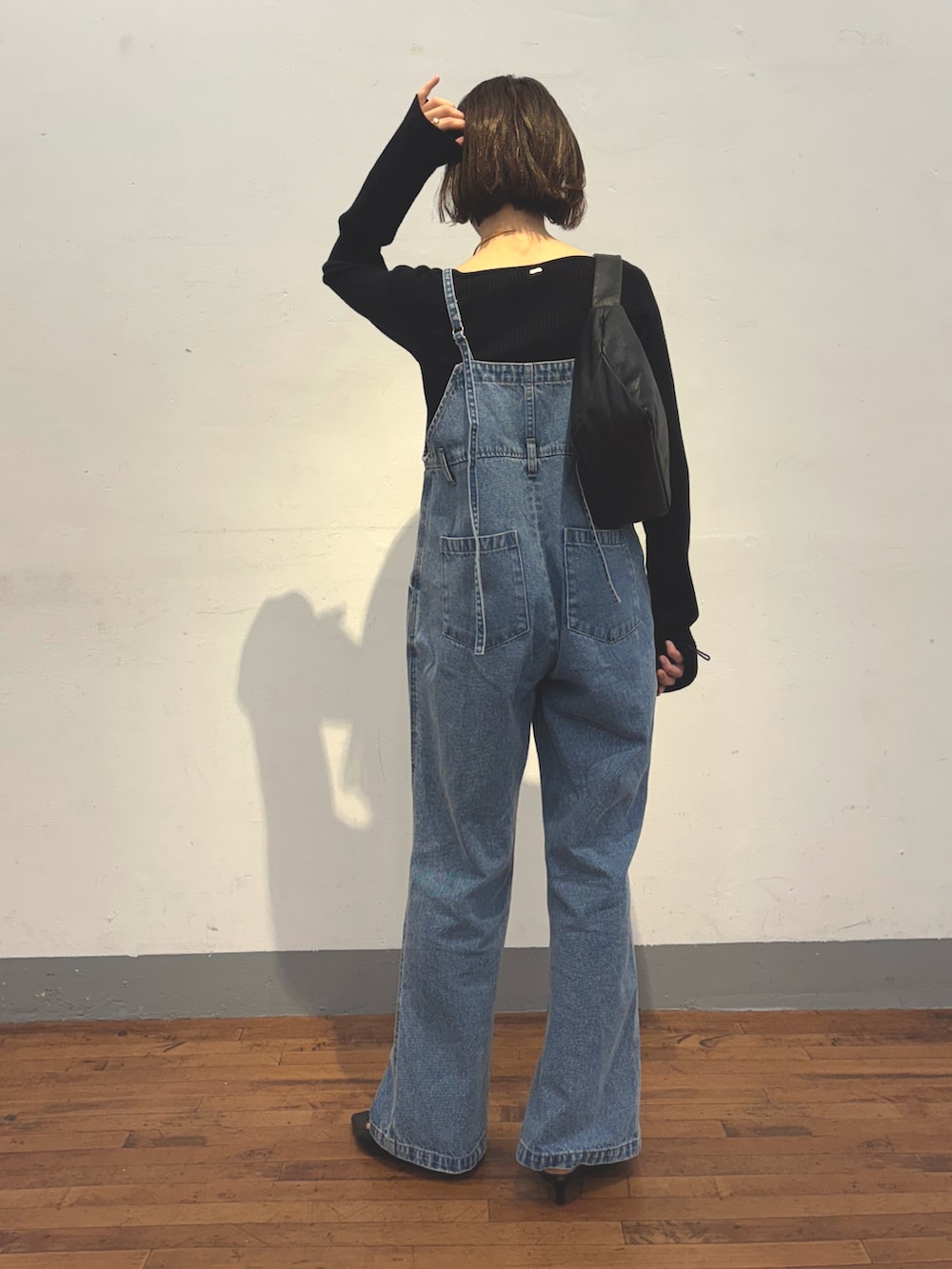ブルー系のサロペット/オーバーオール、ブラック系のショルダーバッグ、ブルー系のニット/セーターを着用したレディースの冬コーディネートの3枚目の写真