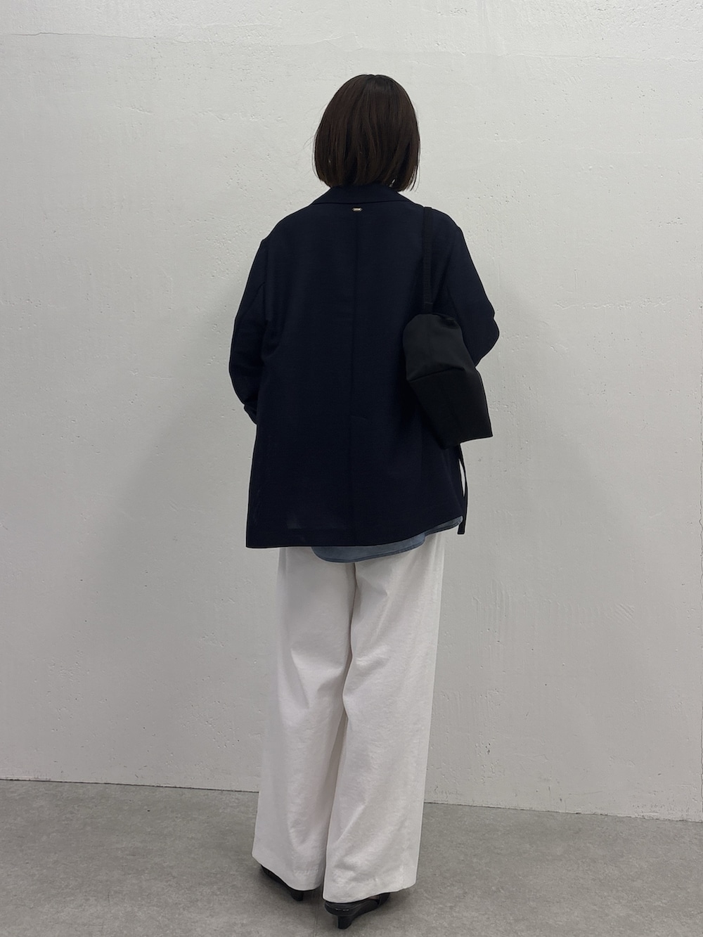 ホワイト系のスラックス、ブルー系のテーラードジャケット、ブラック系のサンダルを着用したレディースの春コーディネートの3枚目の写真