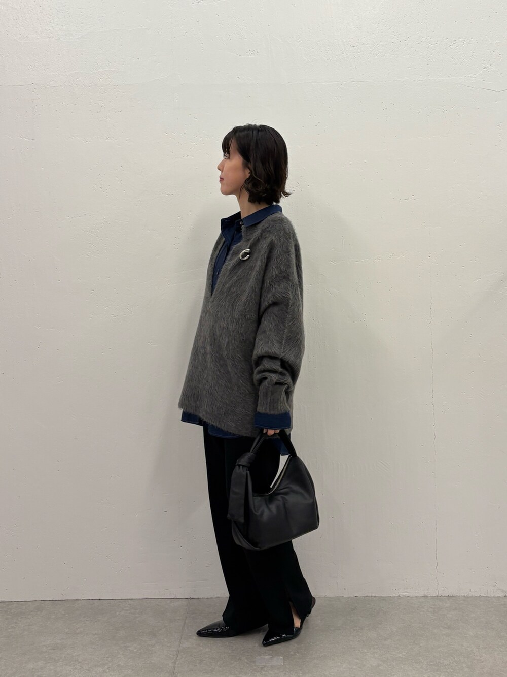 グレー系のニット/セーター、ブルー系のシャツ/ブラウス、ブラック系のパンプスを着用したレディースの秋コーディネートの4枚目の写真