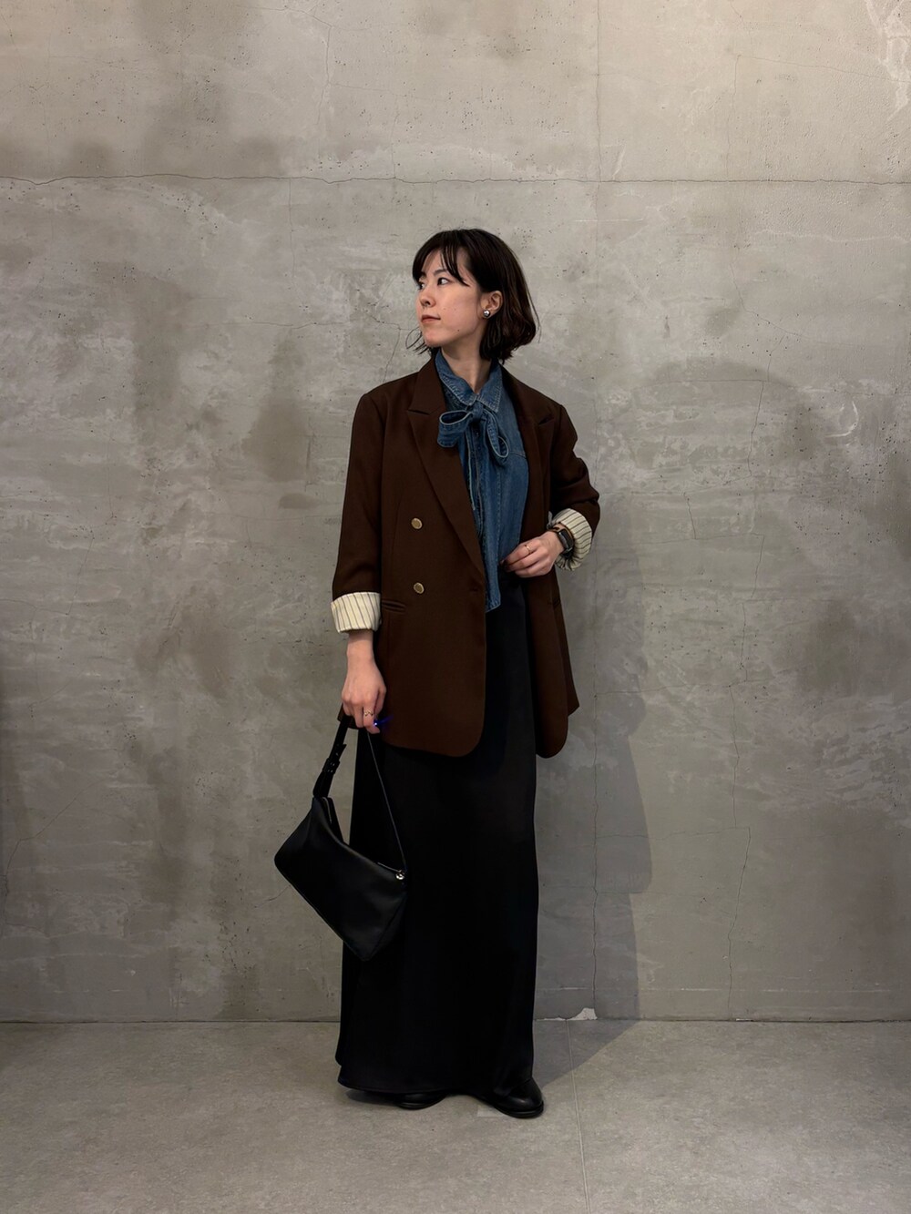 ブラウン系のテーラードジャケット、ブラック系のスカート、ブラック系のブーツを着用したレディースの秋コーディネートの2枚目の写真