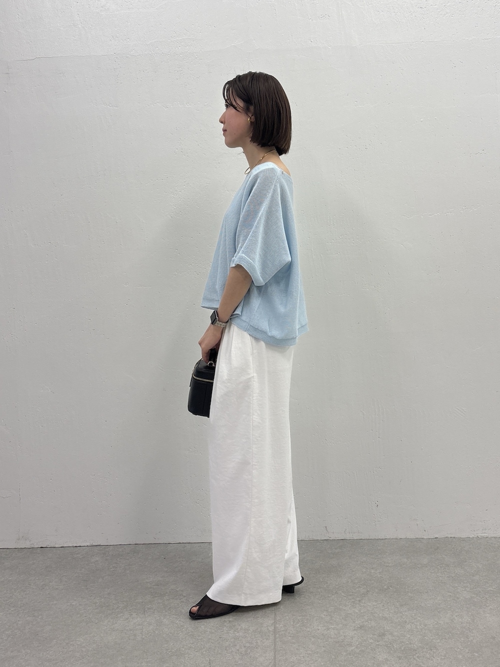 ホワイト系のスラックス、ブラック系のショルダーバッグ、ブラック系のサンダルを着用したレディースの春コーディネートの2枚目の写真