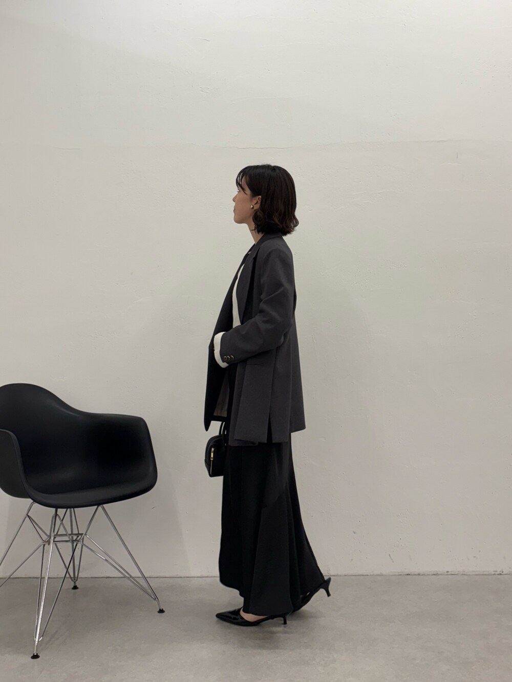 ブラック系のスカート、ブラック系のパンプス、ブラック系のボストンバッグを着用したレディースの秋コーディネートの2枚目の写真