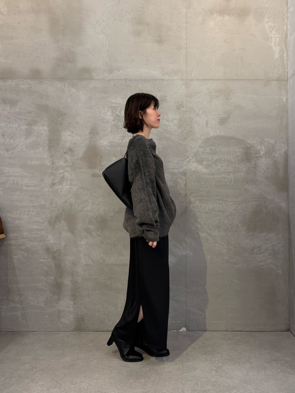 グレー系のニット/セーター、ブラック系のスカート、ホワイト系のTシャツ/カットソーを着用したレディースの秋コーディネートの3枚目の写真