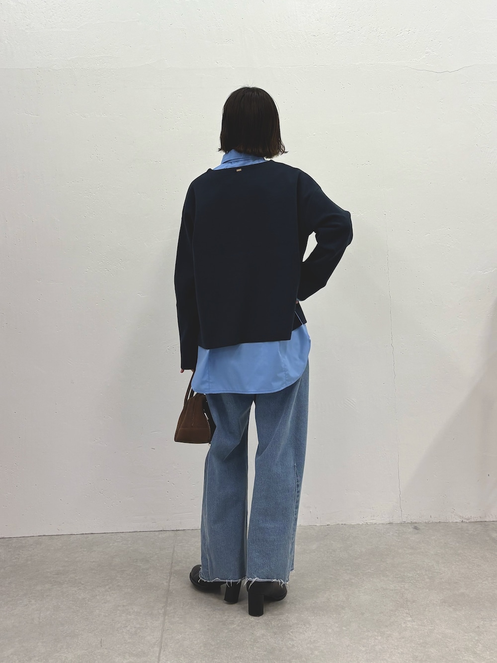 ブラック系のニット/セーター、ブルー系のシャツ/ブラウス、ブルー系のデニムパンツを着用したレディースの秋コーディネートの3枚目の写真