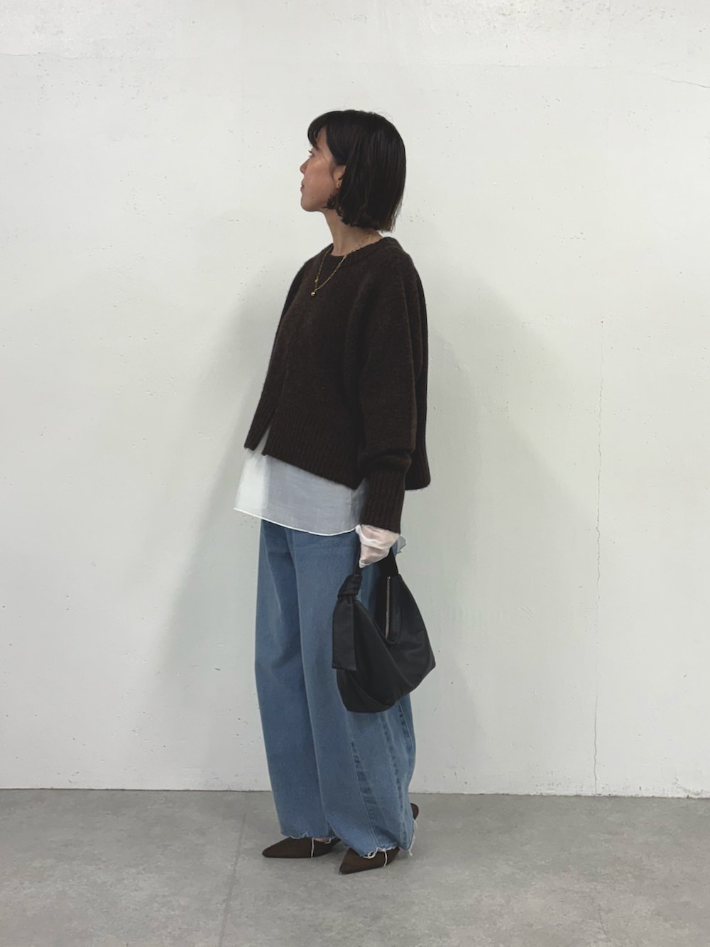 グレー系のニット/セーター、ブルー系のデニムパンツ、ホワイト系のTシャツ/カットソーを着用したレディースの秋コーディネートの3枚目の写真