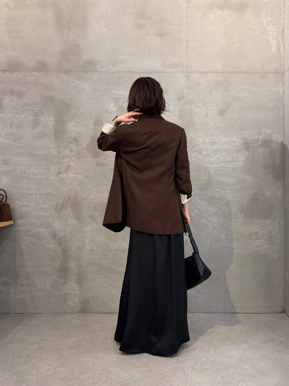 ブラウン系のテーラードジャケット、ブラック系のスカート、ブラック系のブーツを着用したレディースの秋コーディネートの4枚目の写真