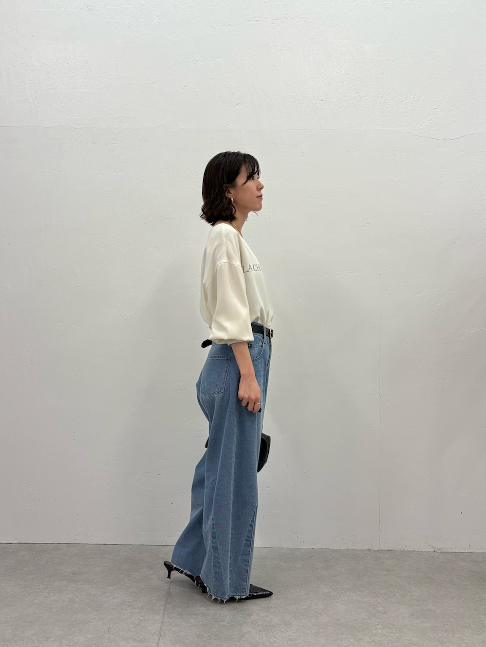 ブルー系のデニムパンツ、ブラック系のパンプス、ブラック系のボストンバッグを着用したレディースの秋コーディネートの2枚目の写真