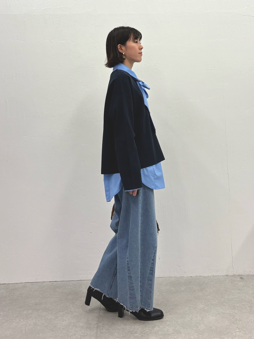 ブラック系のニット/セーター、ブルー系のシャツ/ブラウス、ブルー系のデニムパンツを着用したレディースの秋コーディネートの2枚目の写真