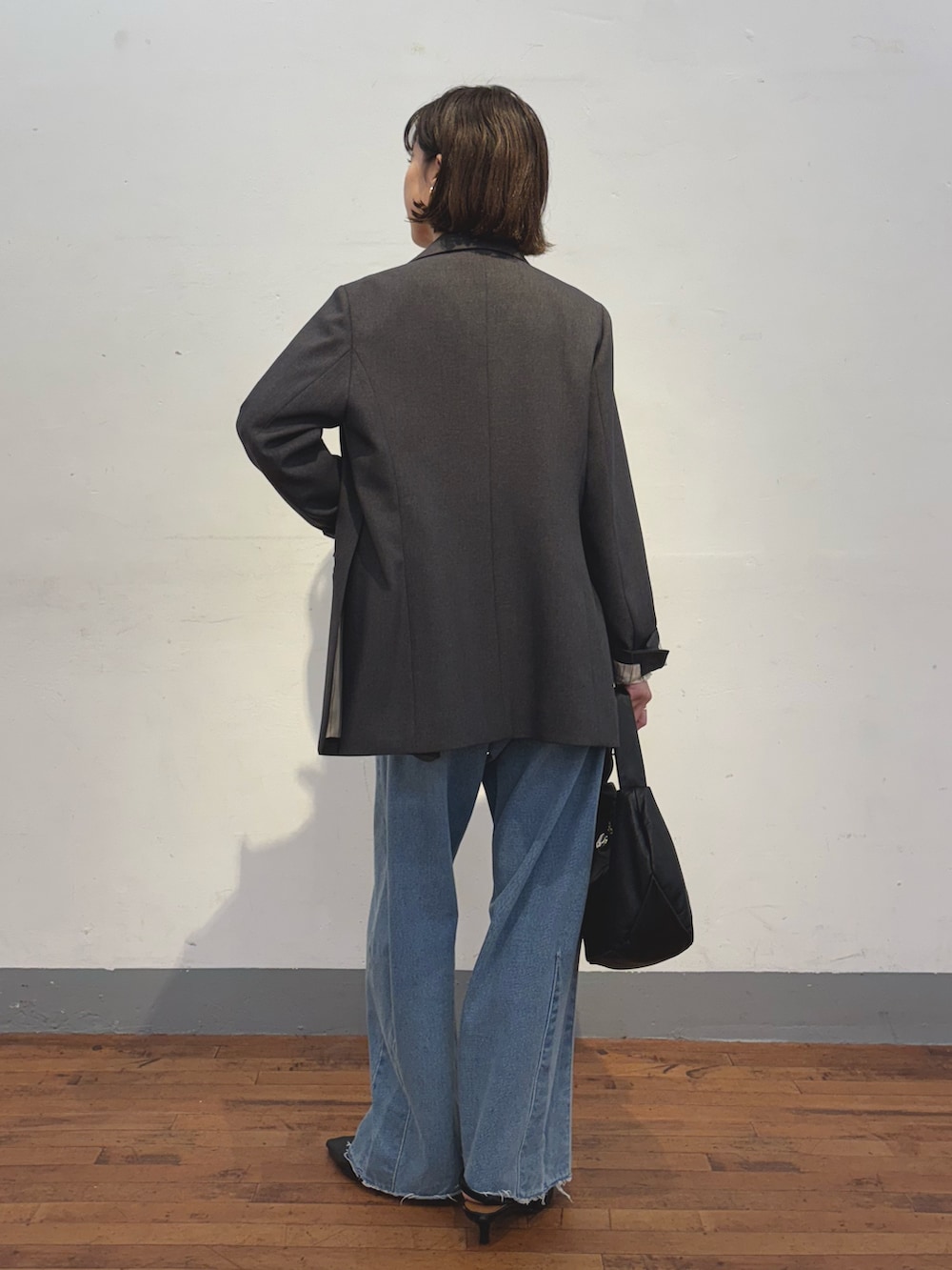 ブルー系のデニムパンツ、ブラック系のショルダーバッグ、グレー系のテーラードジャケットを着用したレディースの冬コーディネートの2枚目の写真