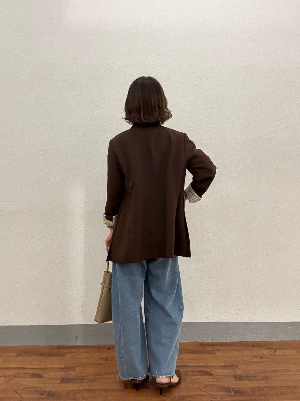 ベージュ系のトートバッグ、ブルー系のデニムパンツ、ブラウン系のパンプスを着用したレディースの秋コーディネートの3枚目の写真