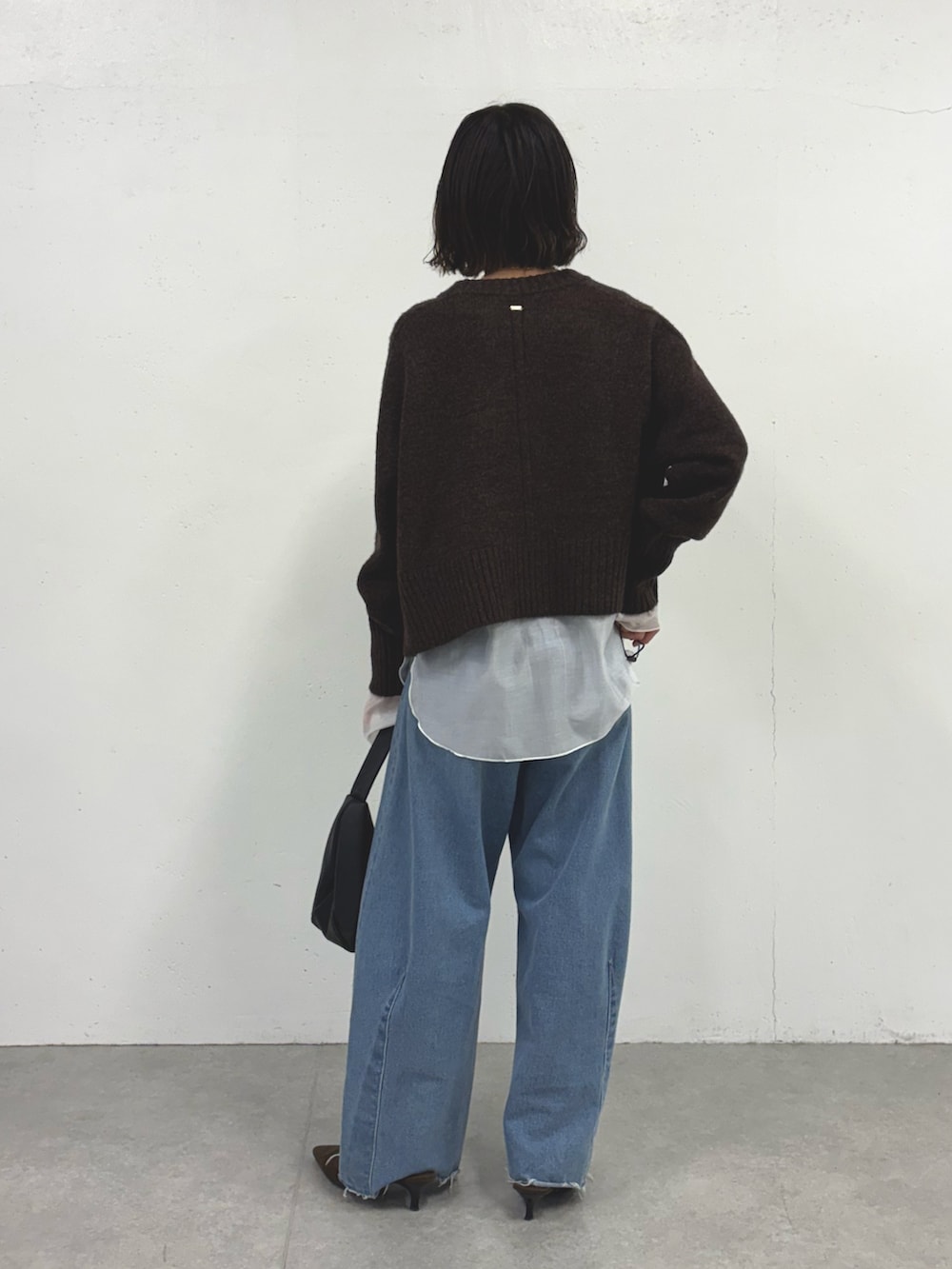 グレー系のニット/セーター、ブルー系のデニムパンツ、ホワイト系のTシャツ/カットソーを着用したレディースの秋コーディネートの2枚目の写真