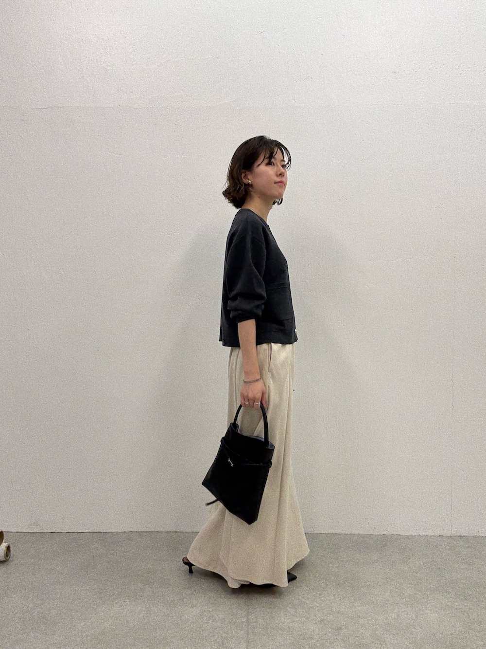 グレー系のカーディガン/ボレロ、ホワイト系のスカート、ブラック系のトートバッグを着用したレディースの夏コーディネートの4枚目の写真