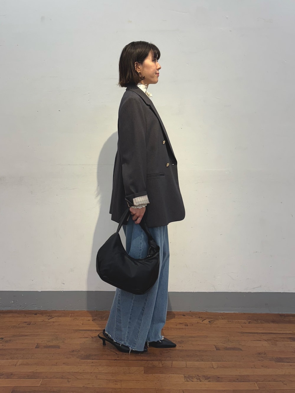 ブルー系のデニムパンツ、ブラック系のショルダーバッグ、グレー系のテーラードジャケットを着用したレディースの冬コーディネートの3枚目の写真