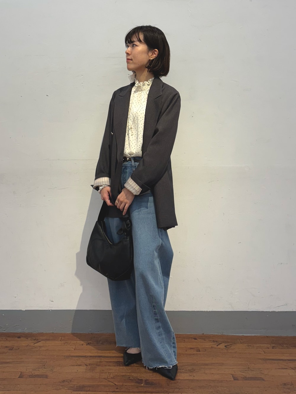 ブルー系のデニムパンツ、ブラック系のショルダーバッグ、グレー系のテーラードジャケットを着用したレディースの冬コーディネートの4枚目の写真