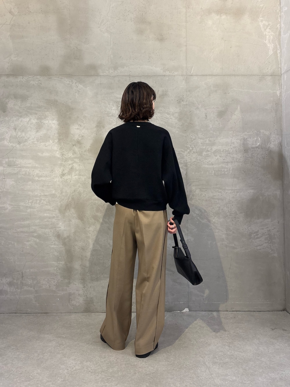 ブラック系のニット/セーター、ベージュ系のスラックス、ブラック系のショルダーバッグを着用したレディースの秋コーディネートの3枚目の写真