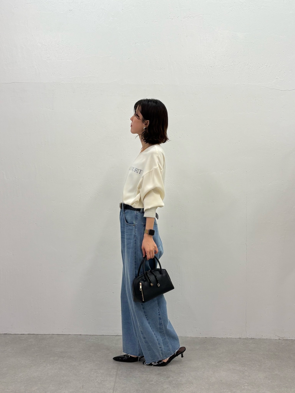 ブルー系のデニムパンツ、ブラック系のパンプス、ブラック系のボストンバッグを着用したレディースの秋コーディネートの3枚目の写真