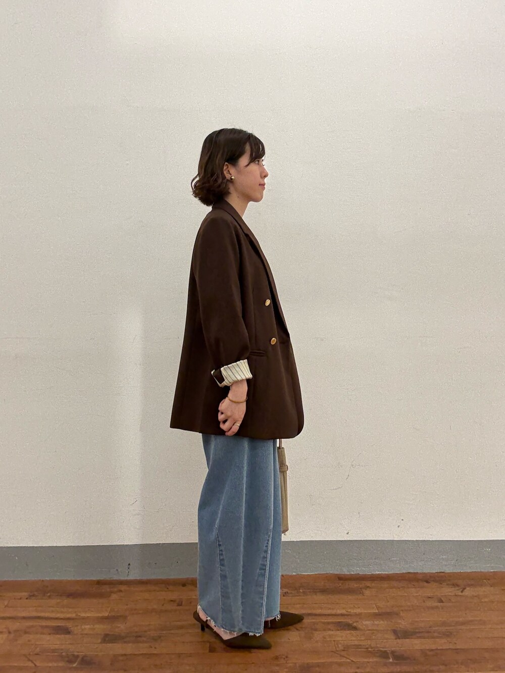 ベージュ系のトートバッグ、ブルー系のデニムパンツ、ブラウン系のパンプスを着用したレディースの秋コーディネートの4枚目の写真