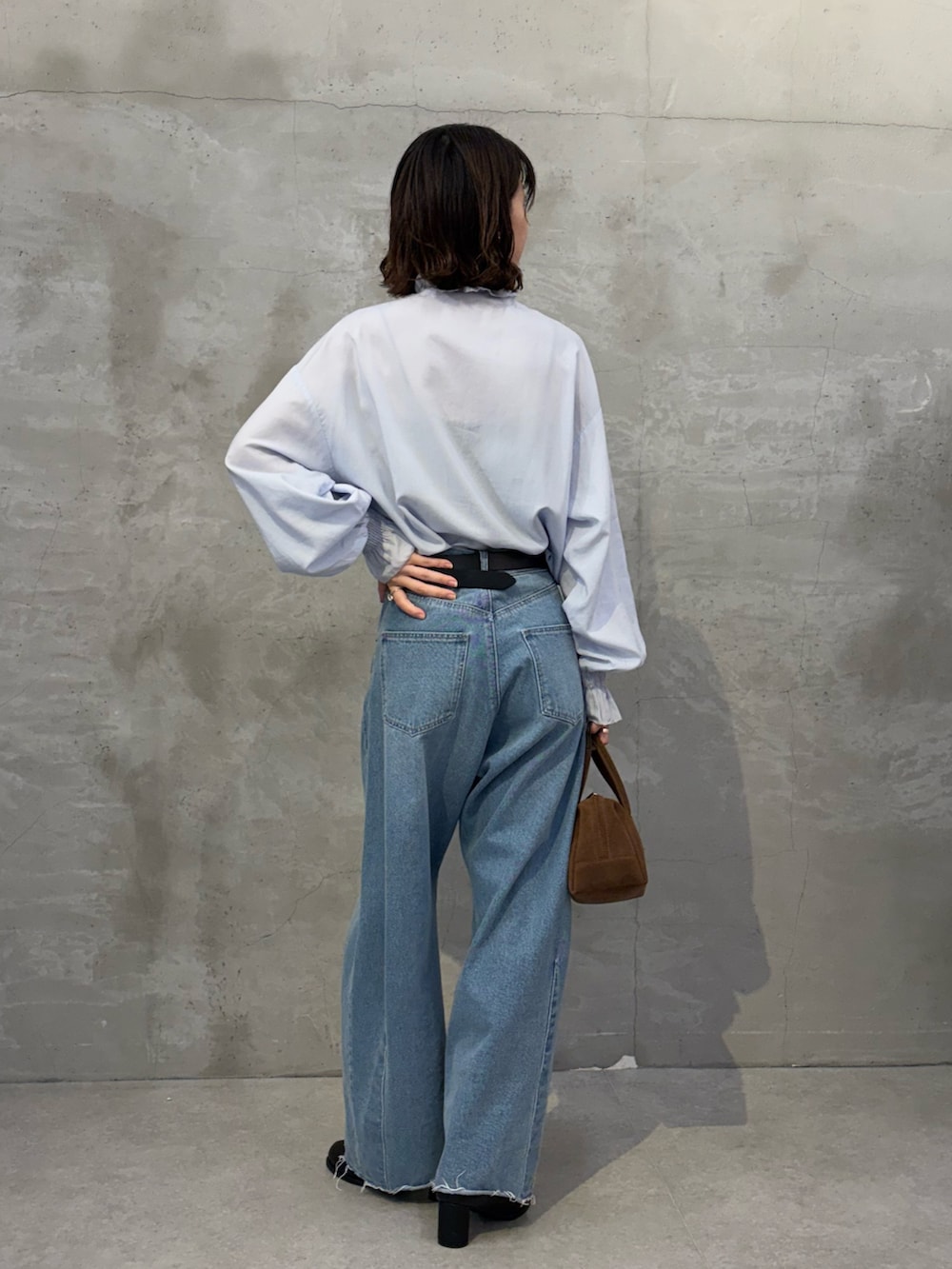 ブラック系のブーツ、ブラウン系のボストンバッグ、ブルー系のシャツ/ブラウスを着用したレディースの秋コーディネートの3枚目の写真